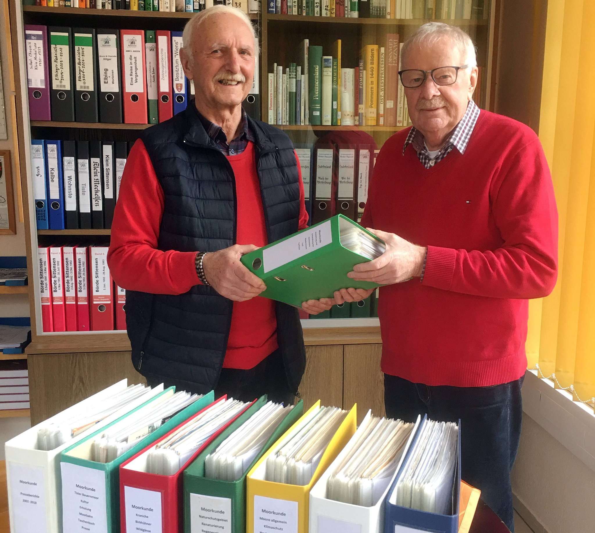 Hans-Günther Beuck (links) übergibt an den Leiter der Sparte Chronik und Schrifttum des Heimatvereins, Hartmut Vollmer, insgesamt acht Ordner mit wissenschaftlich fundierten Informationen zur Moorkunde.