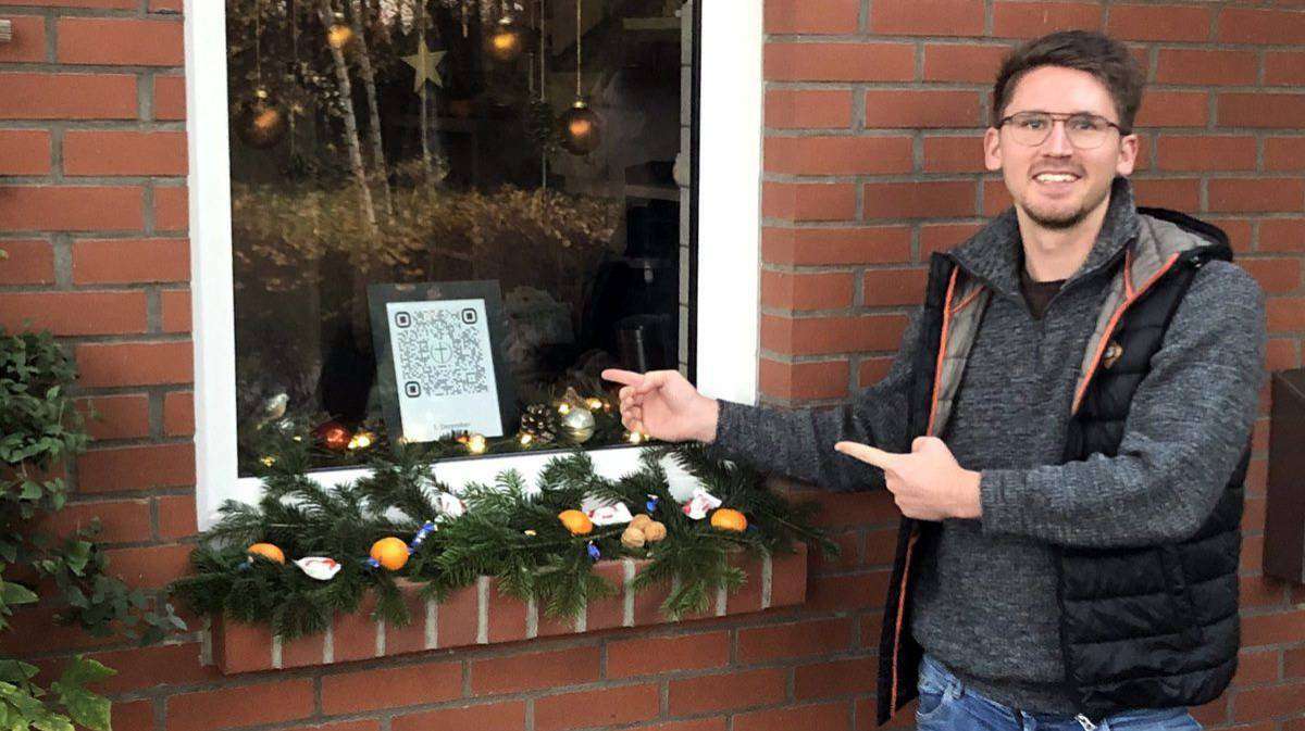 Chris-Simon Bredehöft (Wohnste) zeigt das Adventfenster mit dem QR-Code. Foto: Heidrun Meyer